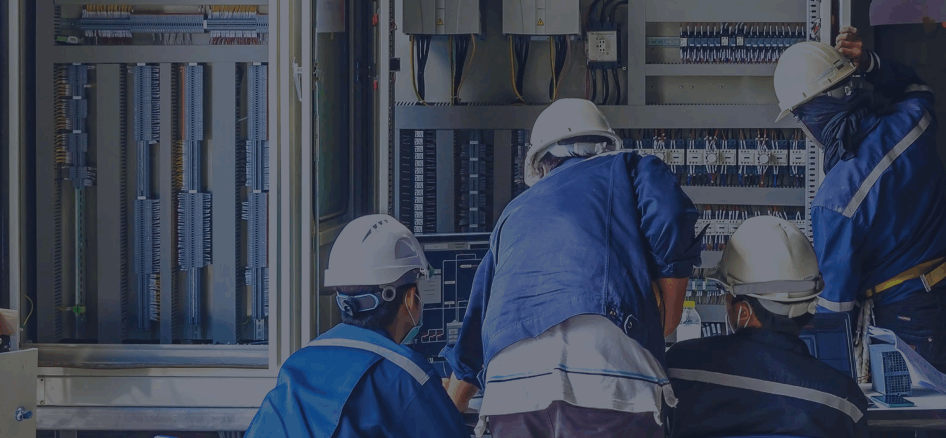 Workers inspecting industrial electrical control panel.